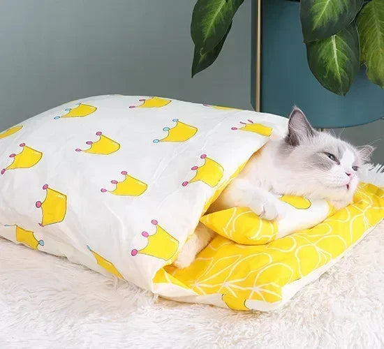 Cat lying on a yellow and white patterned cat nest blanket with cartoon crowns.