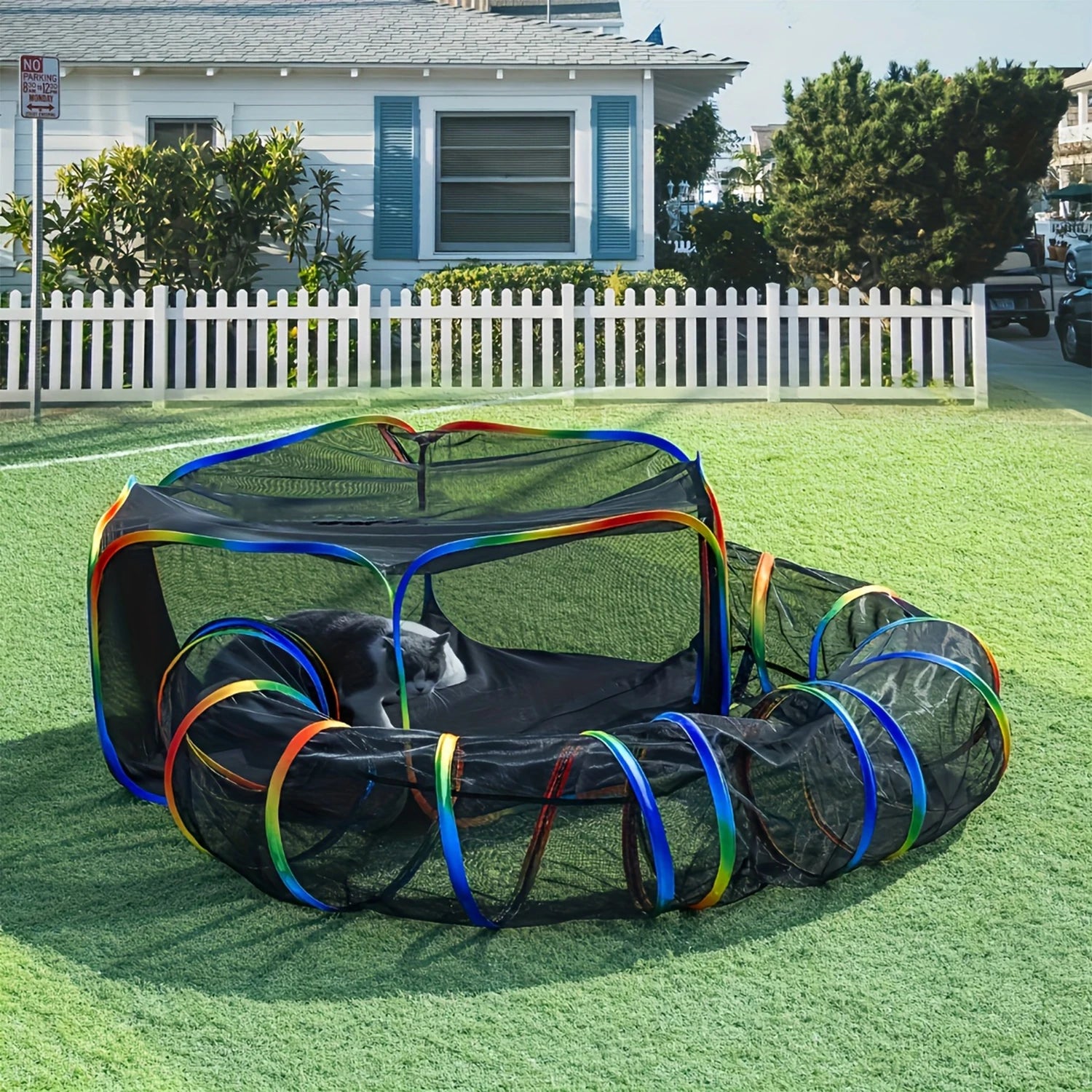 Pet playpen with rainbow-colored tunnels on a grassy area in front of a house.