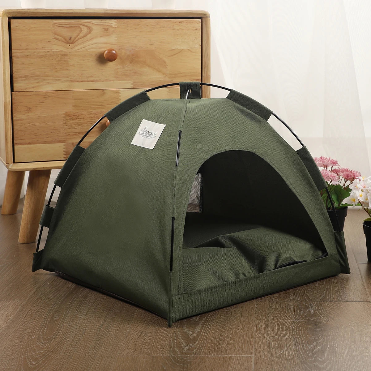 Green pet tent on a wooden floor with a wooden dresser in the background
