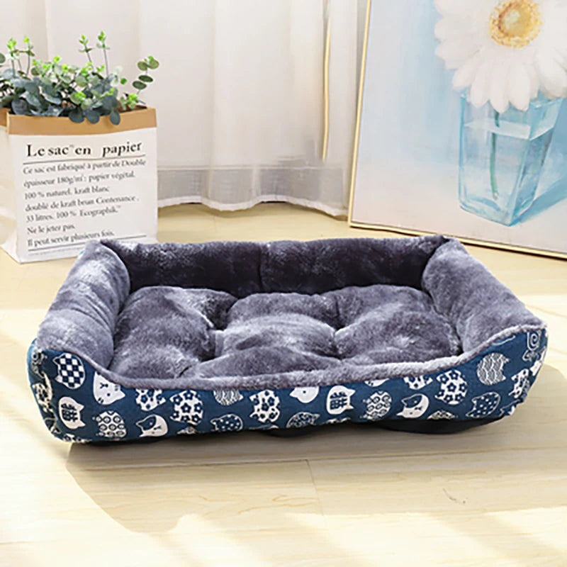 Blue pet bed with white patterns on a light wooden floor.