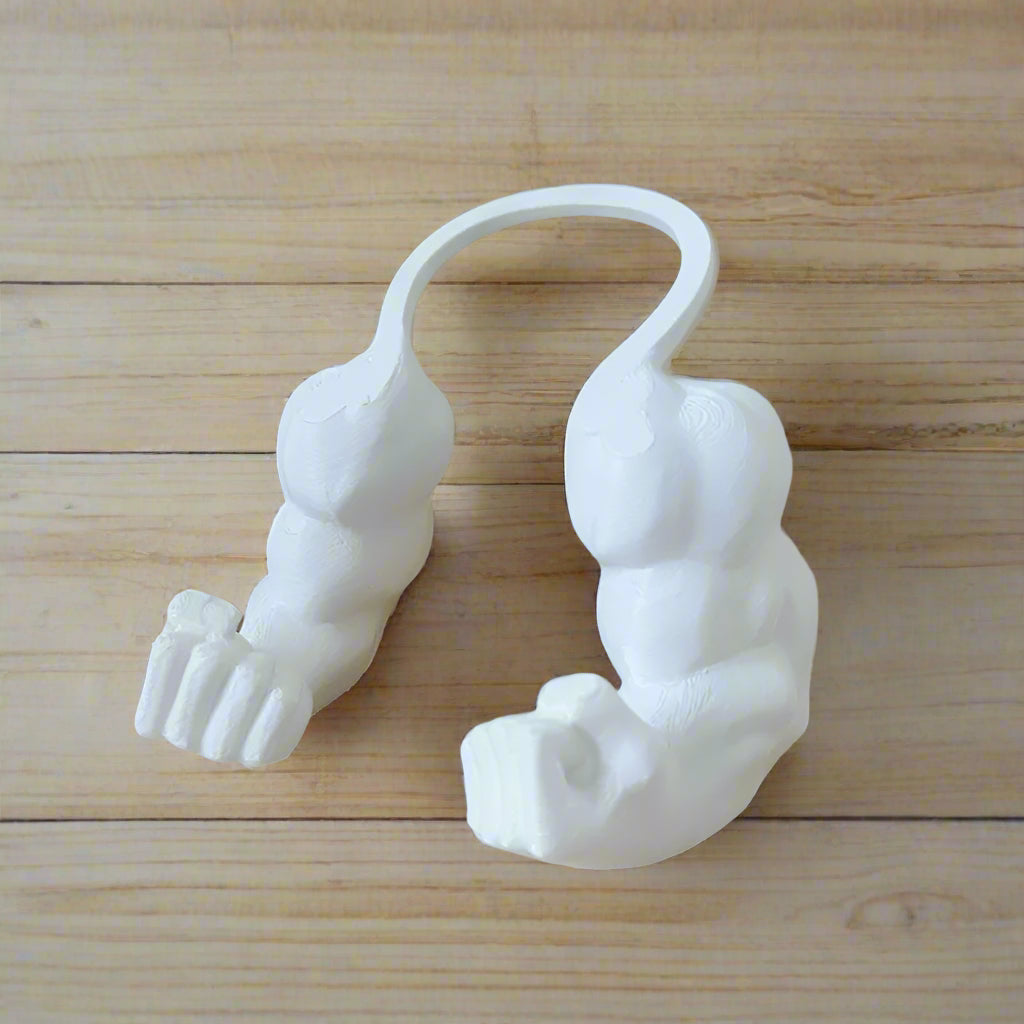 White 3D-printed object resembling a creature on a beige surface