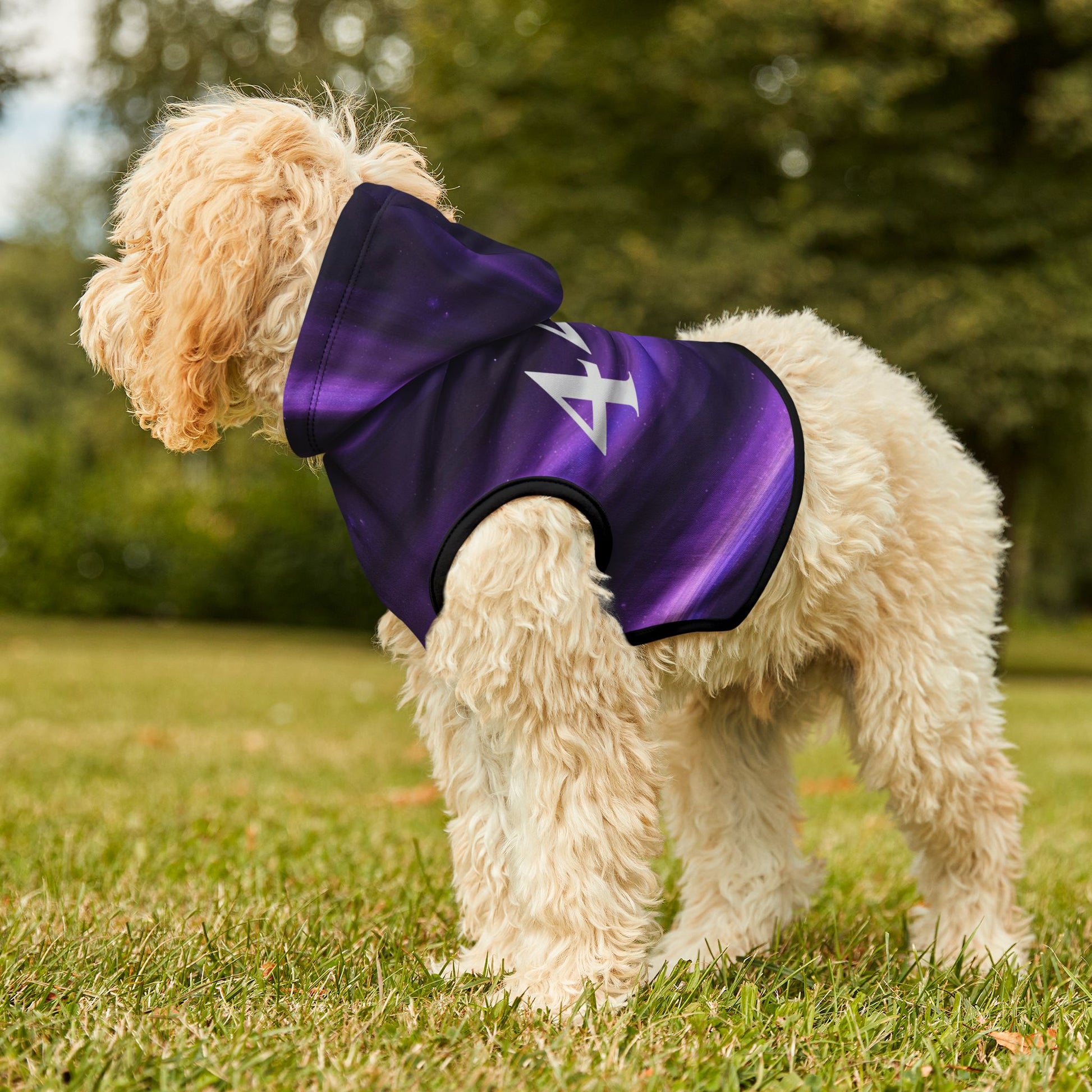 Dog wearing a purple jacket with a white logo on grass