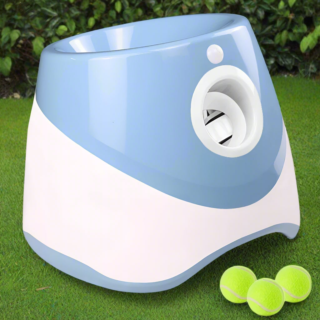 Light blue and white PawFetch automatic ball launcher on grass with three 2 inch mini tennis balls in front