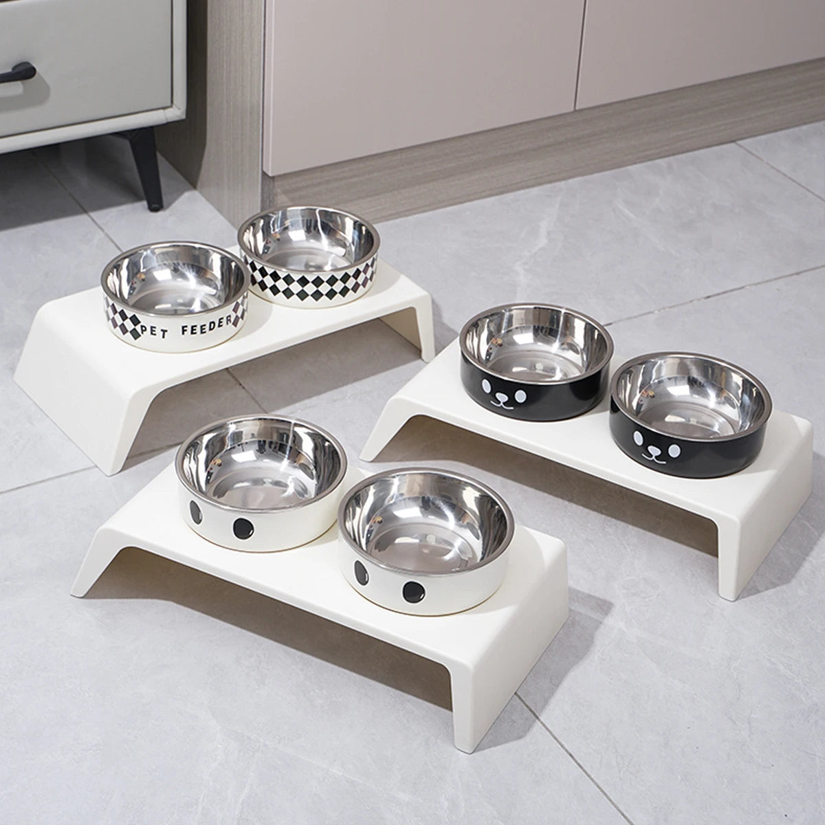 Set of stainless steel pet bowls on white stands in a kitchen setting
