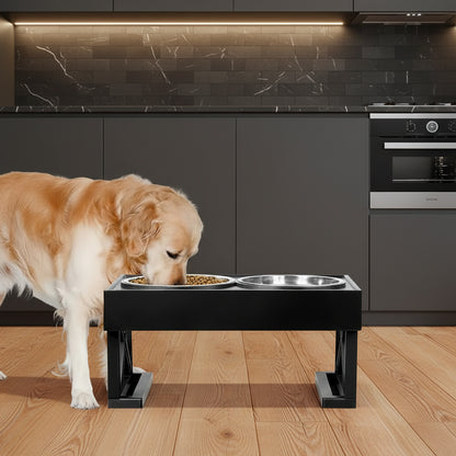 Black adjustable elevated dog bowl stand with stainless steel and slow-feeder bowls on a wooden floor, soft daylight, plant in background.
