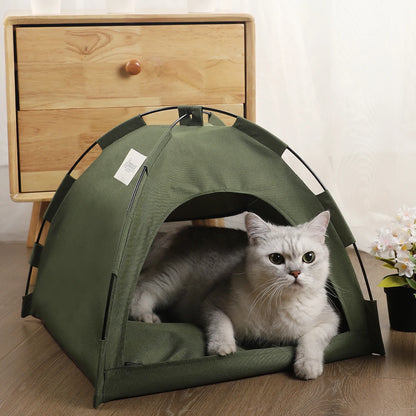 Army green canvas dome cat tent set up on a light wood floor, cat curled inside on the reversible cushion