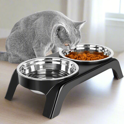 Black elevated pet bowl stand holding two stainless steel bowls on a light grey surface, front-facing view