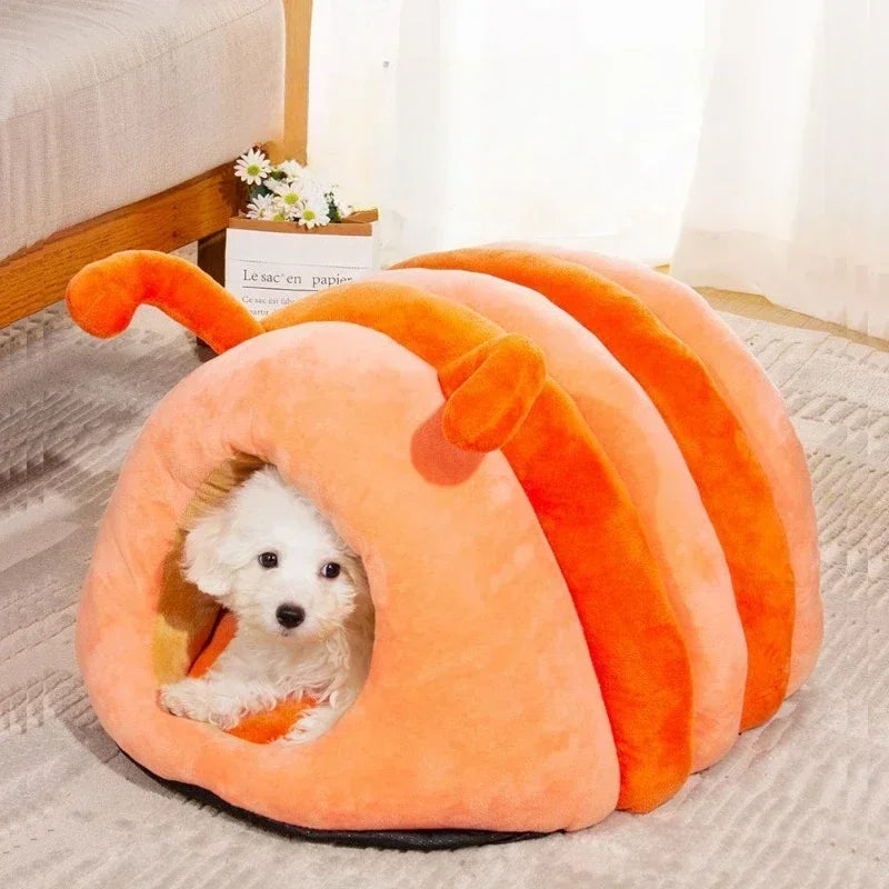 PawWorm caterpillar cave bed in orange — small dog inside the fully enclosed plush tunnel