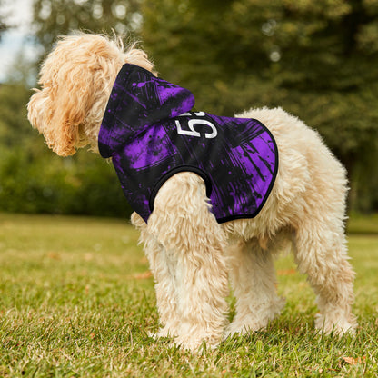 Dog wearing a purple and black jacket with number 555 on grassy area