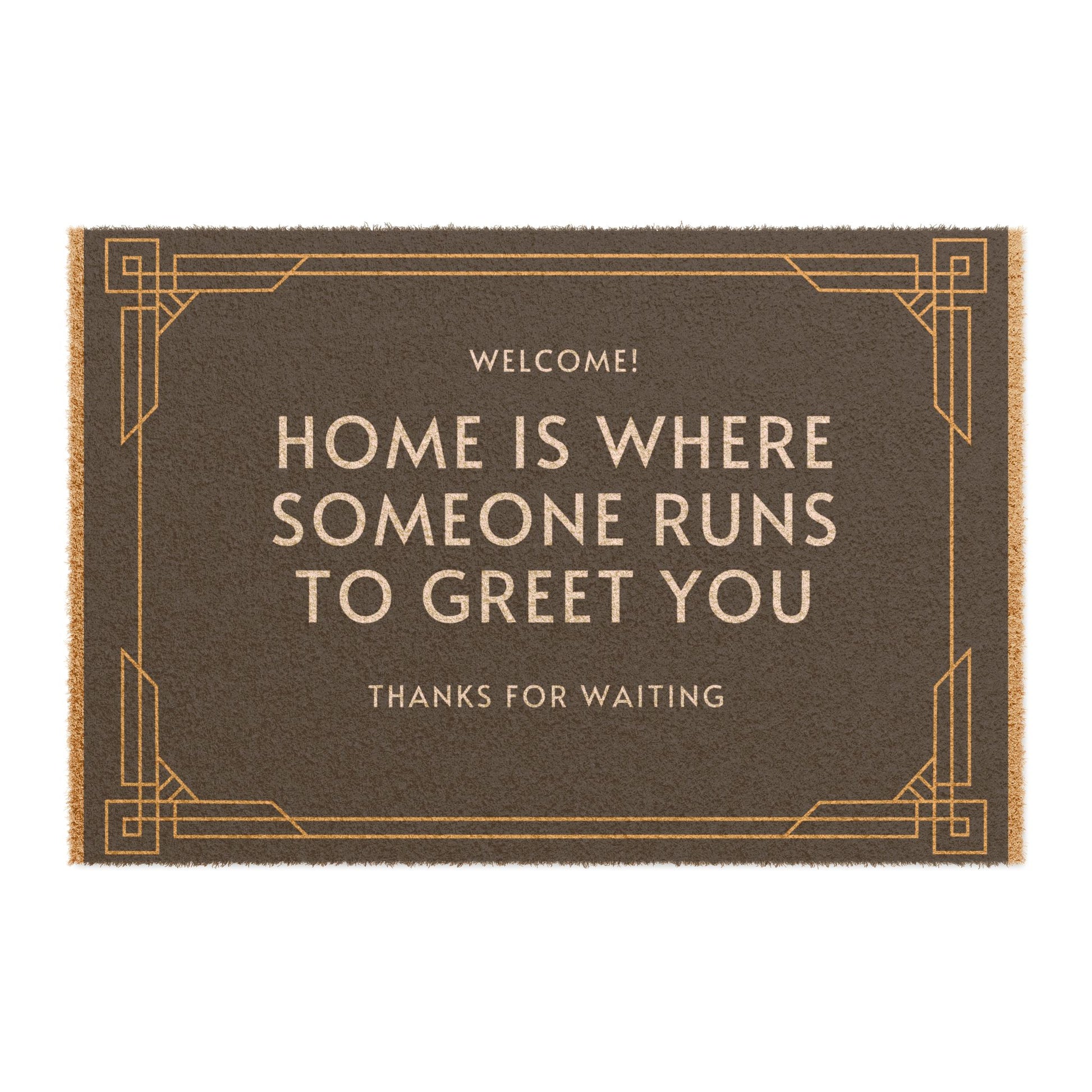 A rectangular doormat with the text 'WELCOME! HOME IS WHERE SOMEONE RUNS TO GREET YOU THANKS FOR WAITING' printed in black and gold colors.