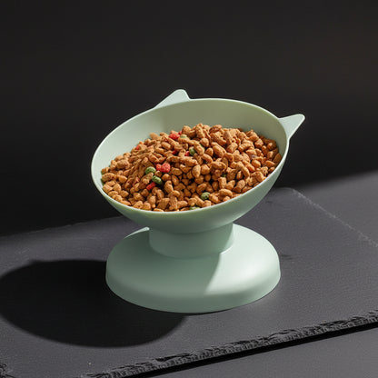 Elevated white pet bowl filled with cat food, placed on a wooden surface with a red and white checkered cloth in the background.
