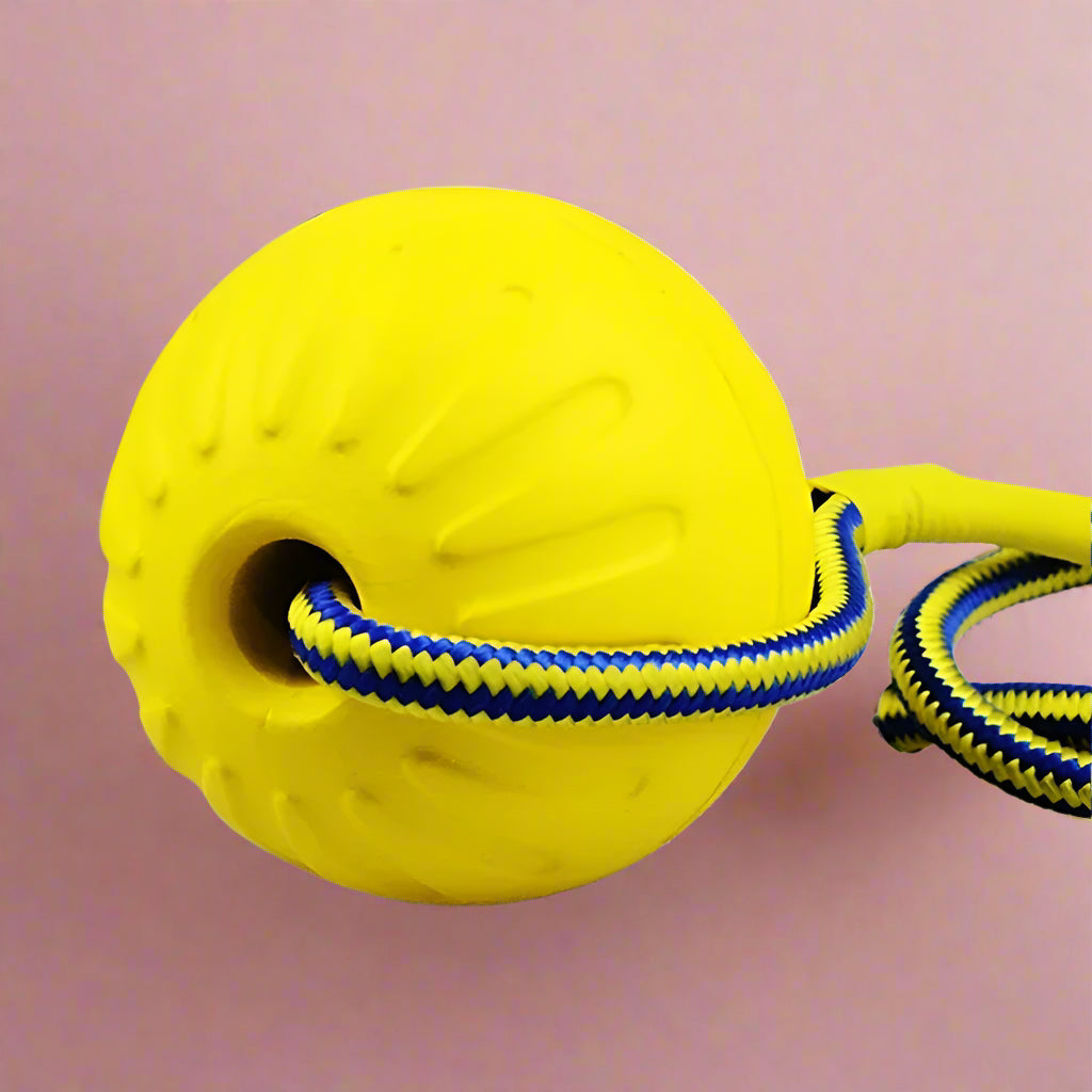 Yellow rubber ball on braided rope close-up showing rope threading through ball