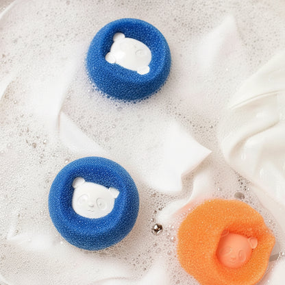 Two blue PawCatch sponge balls floating in soapy water with white fabric to one side.