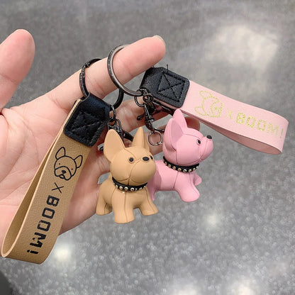 Pink PawCharm French Bulldog keychain held in hand, showing studded collar detail. 