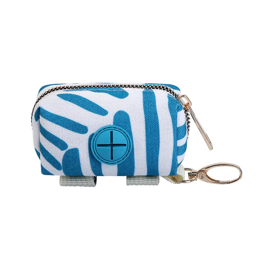 Blue and white brushstroke canvas dog poop bag holder with central dispensing port and gold carabiner attachment clip.