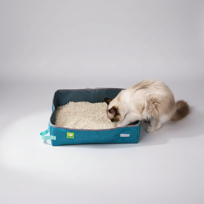 A long-haired cat using a PawPort blue foldable travel litter box filled with cat litter on a tiled floor.