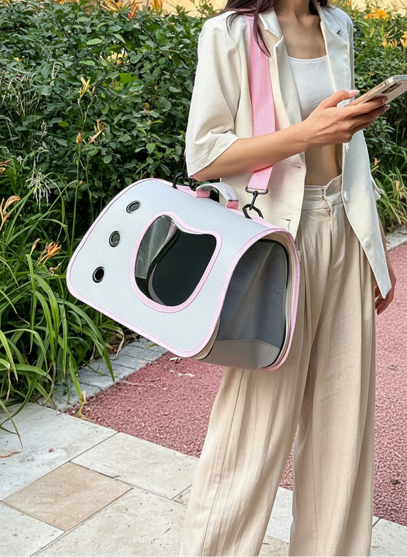 Person holding a pet carrier outdoors with greenery in the background