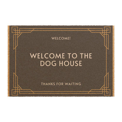 A brown coir doormat with a black vinyl backing, featuring the text 'WELCOME TO THE DOG HOUSE' in capital letters on a plain background.